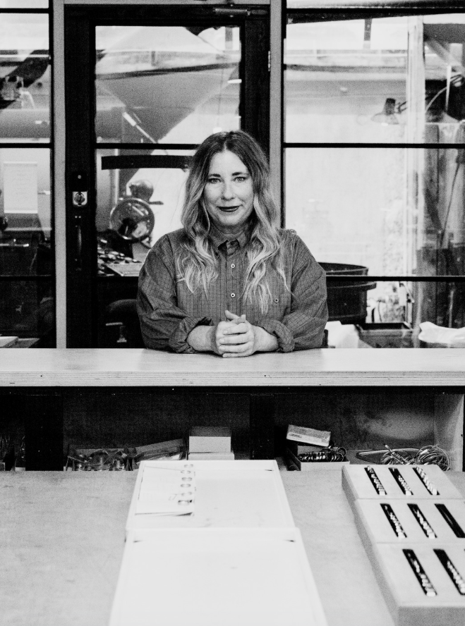 Person sitting at a desk in an office setting with large windows.